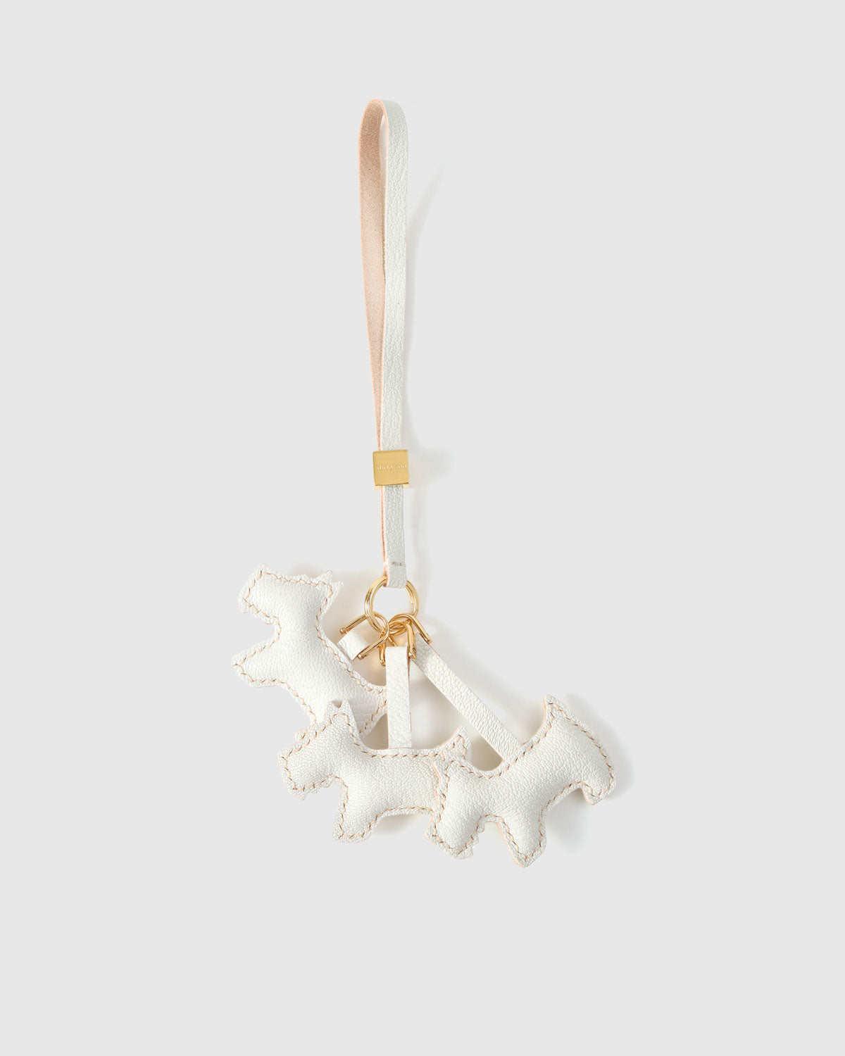 Triple Schnauzer charm handmade from French Alran genuine goatskin and French suede — real full-grain leather from Tarn, since 1903. 3 days of hand-cutting, hand-stitching, hand-layering. Arrives in luxury gift packaging. Designed in Amsterdam.