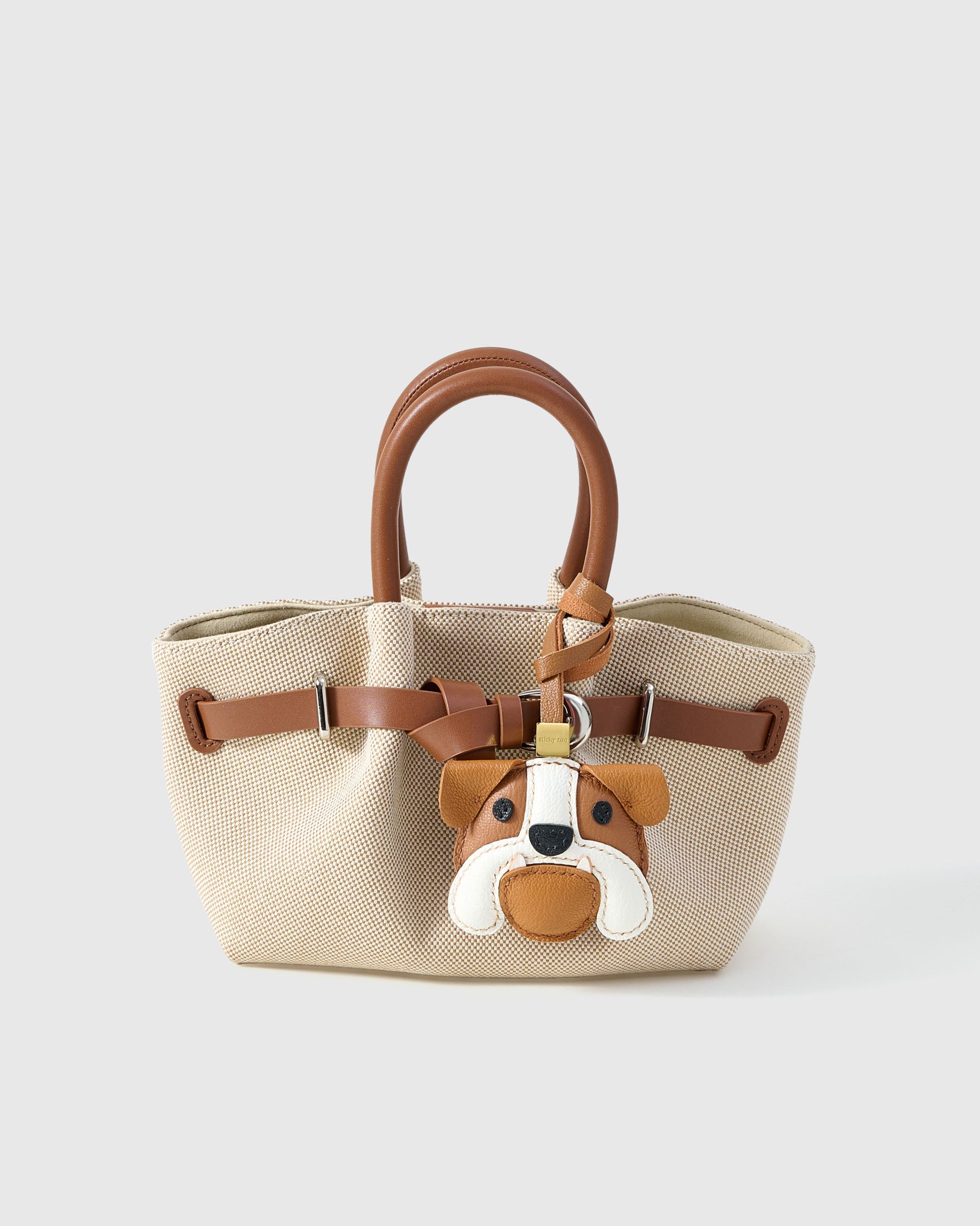 Close-up of handmade Bulldog leather bag charm — hand-layered face panels in French Alran goatskin, embroidered eyes. STICKYZOO 3-day build.