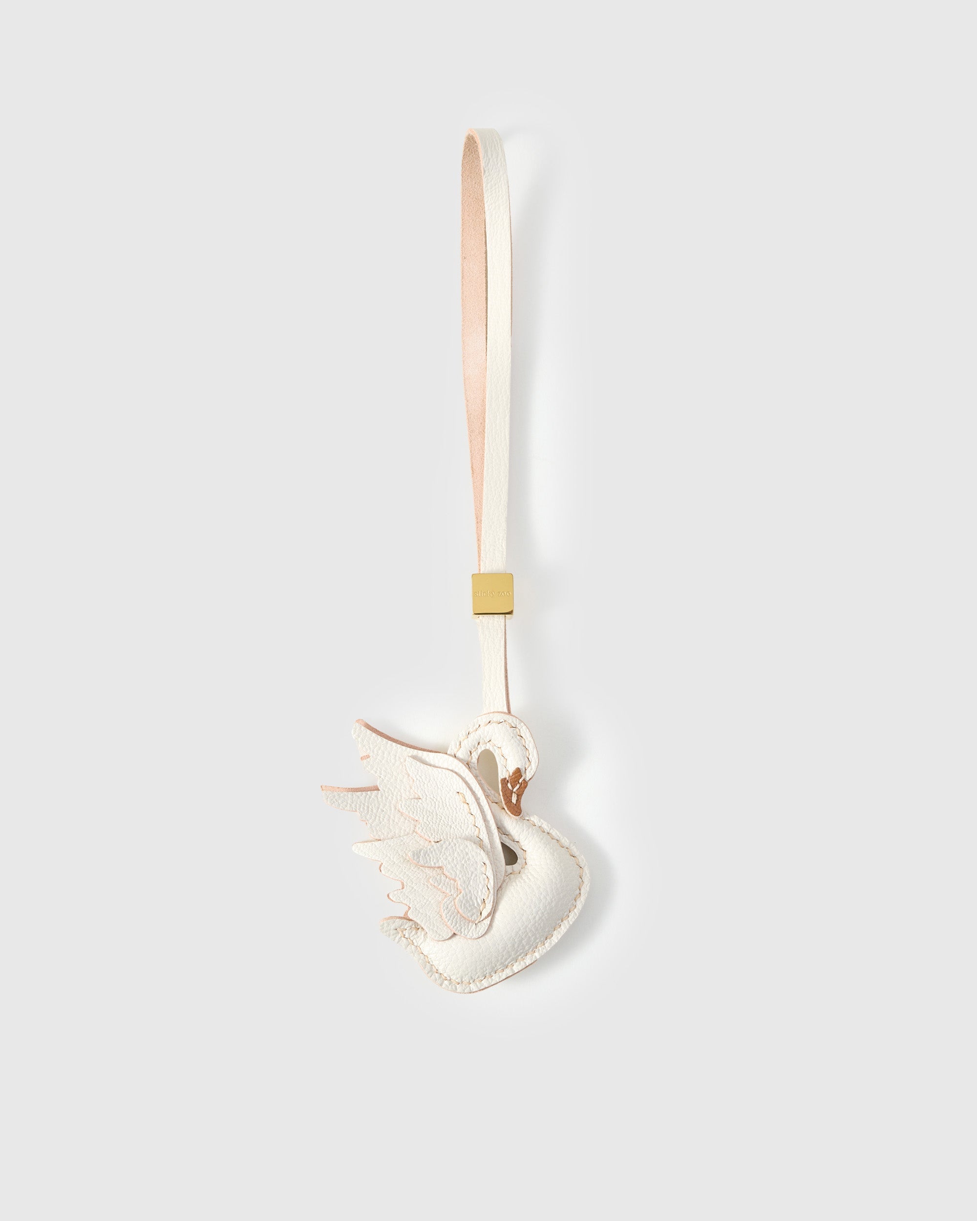 Handmade leather swan bag charm by STICKYZOO — French Alran goatskin hand-layered and hand-stitched by one artisan over 3 days. Handmade leather strap with engraved 18K gold-plated cube. Designed in Amsterdam.