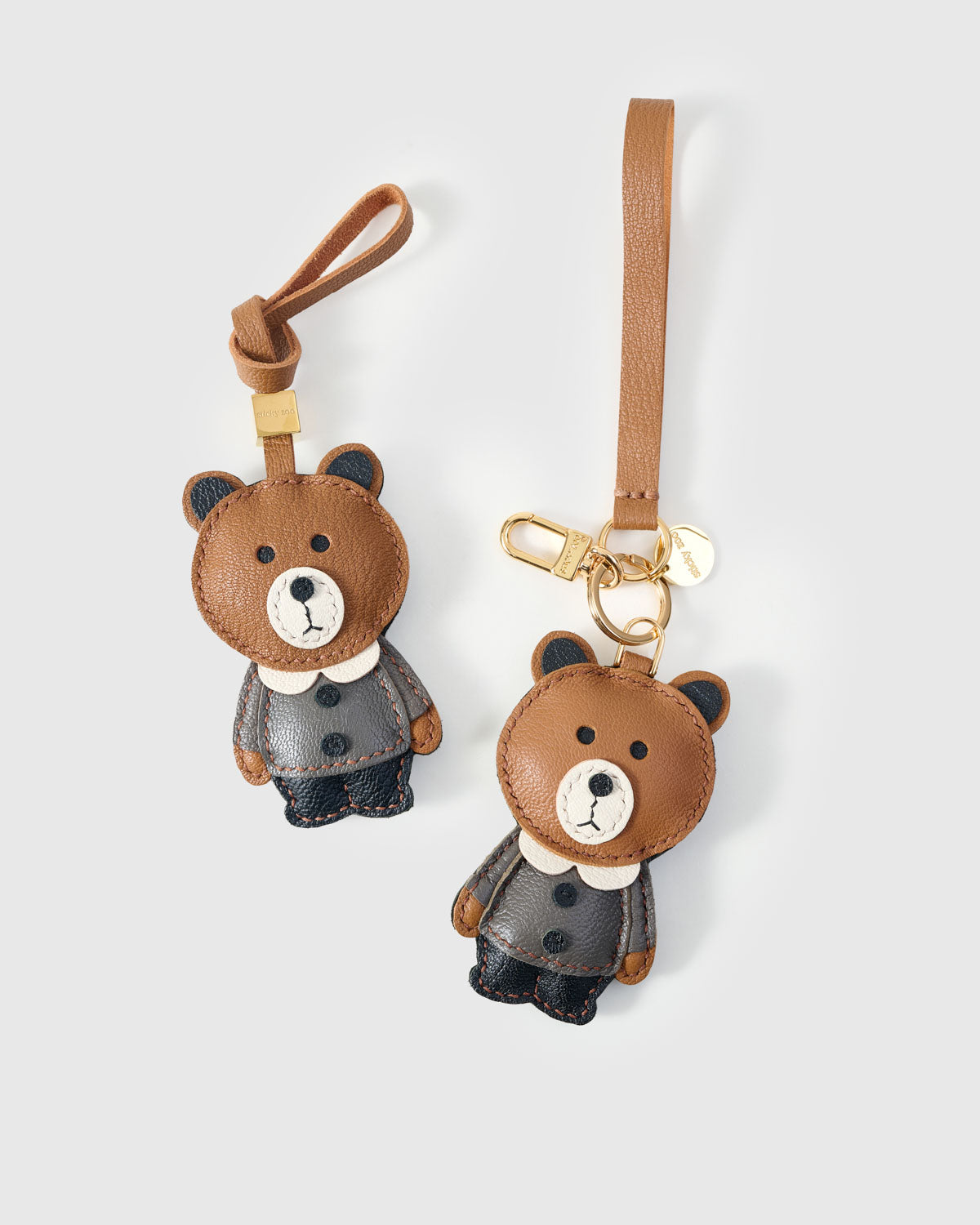 Both editions of the teddy bear charm — leather strap loop for bags, or 18K gold-plated keychain clip.