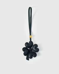 STICKYZOO Lucky Clover Charm in black French Alran goatskin — four padded heart-shaped petals in a sculptural 3D form, gold-plated hardware. 3-day handmade piece.