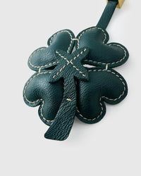 STICKYZOO Lucky Clover Charm clipped to a handbag — handmade French Alran goatskin in forest green padded 3D. 3-day artisan build.