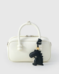 Black dinosaur charm styled on a bag — a small, specific piece that turns a simple bag into a personal one.