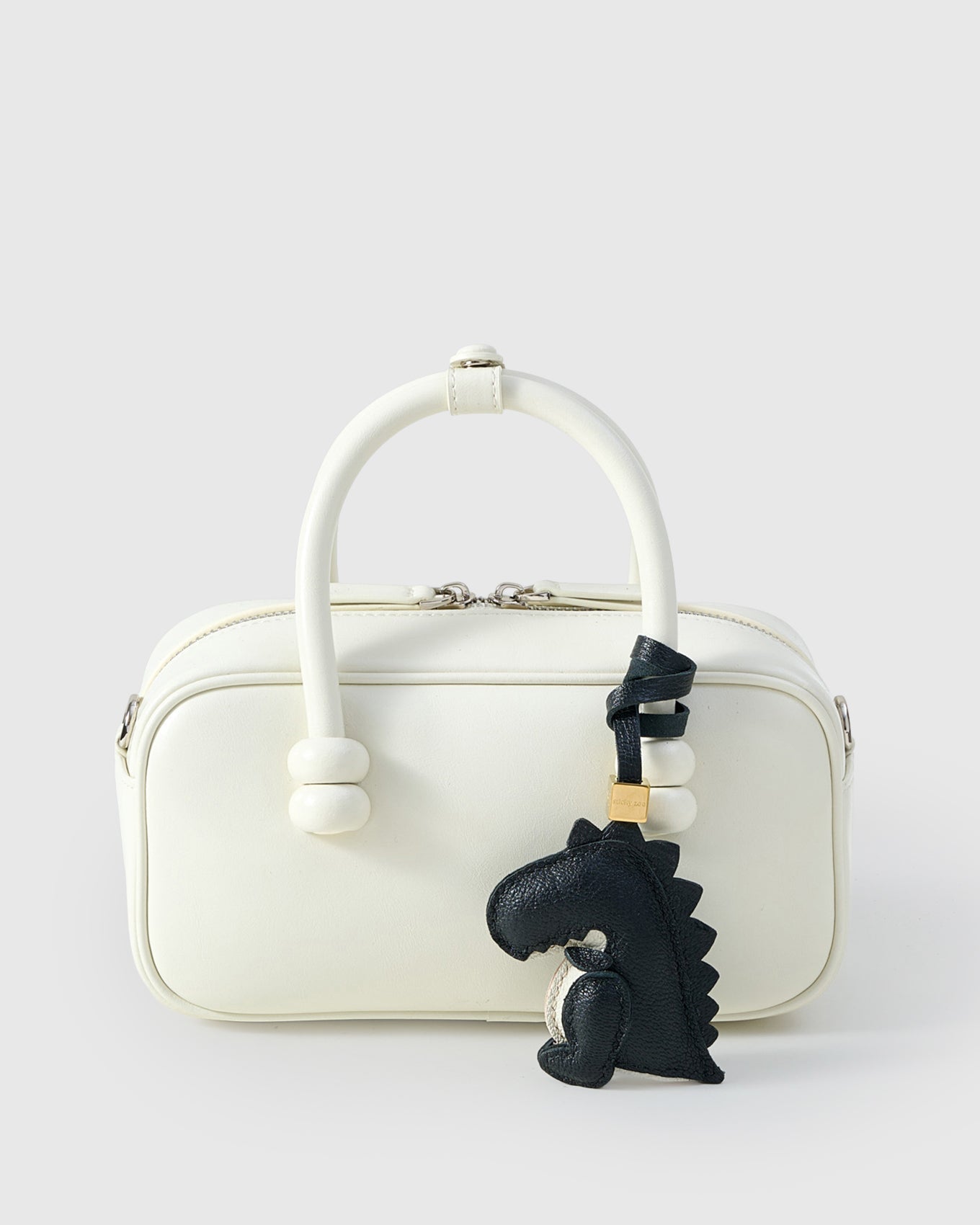 Black dinosaur charm styled on a bag — a small, specific piece that turns a simple bag into a personal one.