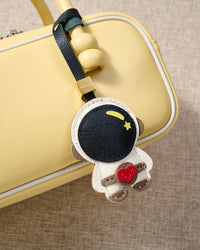 Close-up of the astronaut charm — hand-cut and hand-stitched panels of French Alran goatskin. Every layer by hand.