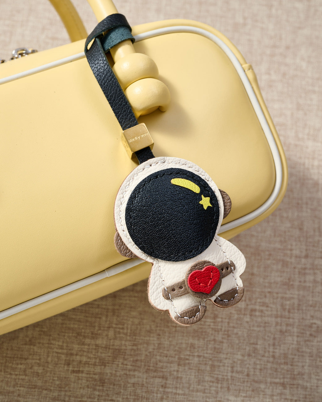 Close-up of the astronaut charm — hand-cut and hand-stitched panels of French Alran goatskin. Every layer by hand.