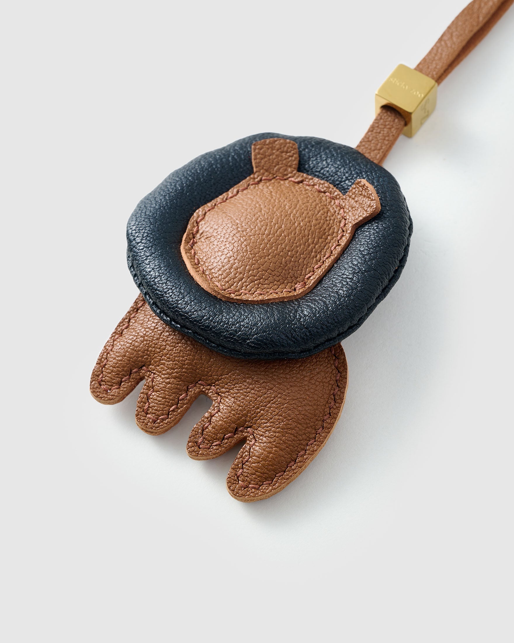 LION CHARM on an 18K gold-plated keychain clip with engraved STICKYZOO disc — clips to keys, bags or backpacks.