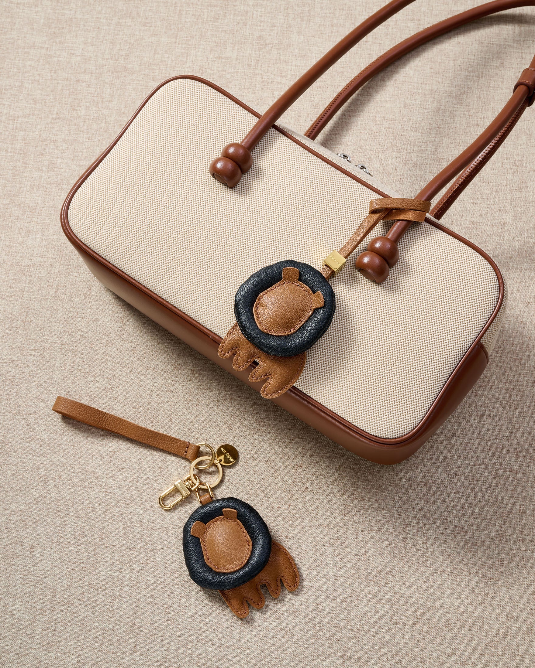 Close-up of the lion charm — hand-cut and hand-stitched panels of French Alran goatskin. Every layer by hand.