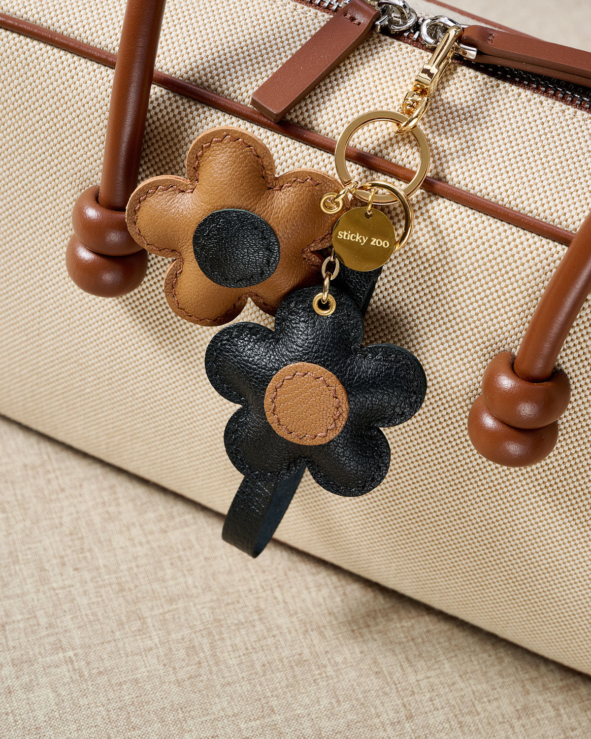STICKYZOO Twin Flowers Charm — hand-cut, hand-stitched twin five-petal blooms on gold keychain in French Alran goatskin. Designed in Amsterdam.