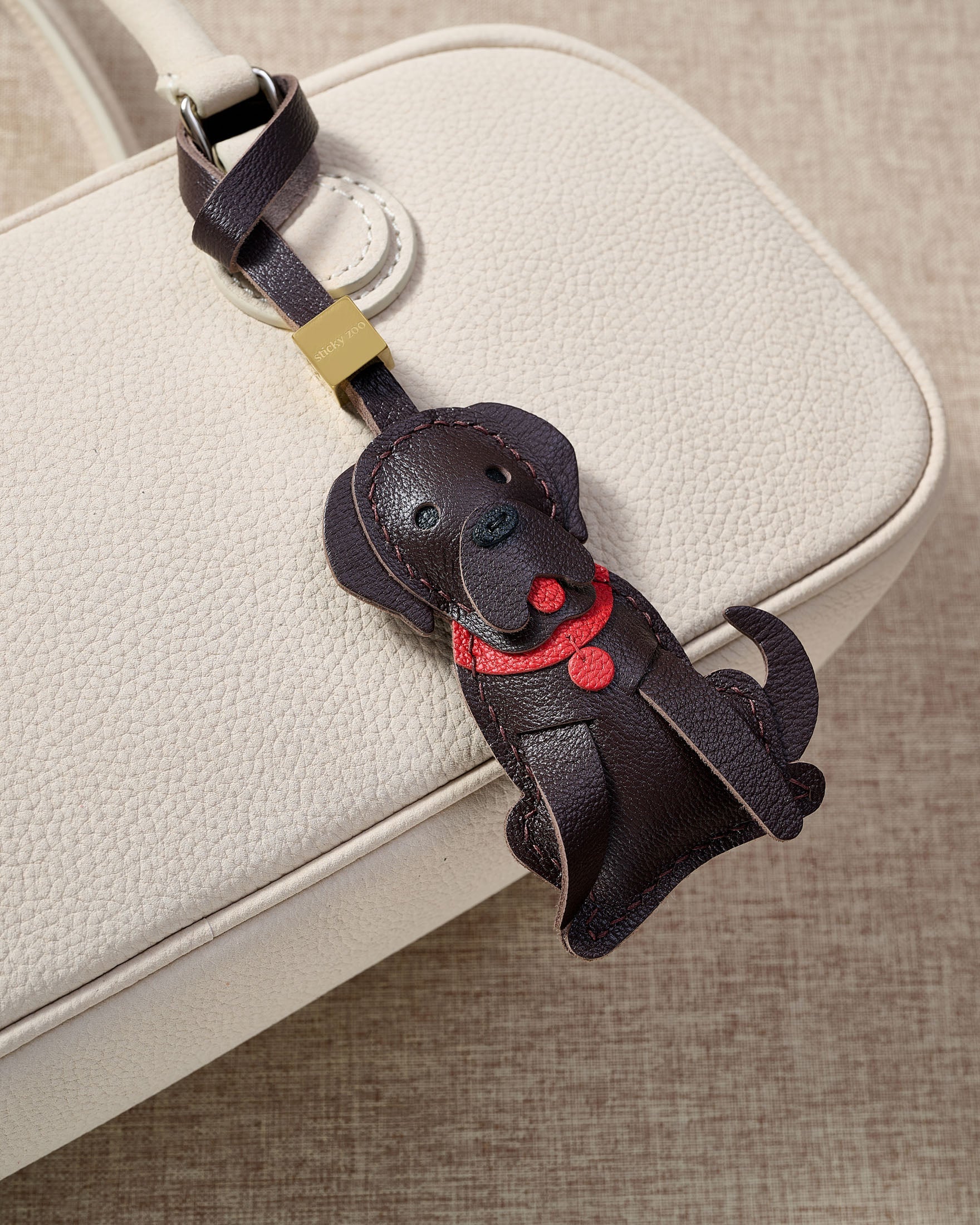 Handmade Golden Retriever leather bag charm on a handbag — 5 days of hand-cutting, stitching, and layering in French Alran goatskin. STICKYZOO.