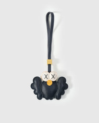 Black Hootie the Owl charm handmade from French Alran genuine goatskin — deep black body, spread wings, cream-ringed X-stitched eyes, orange beak, navy leather strap. Three days by hand. Arrives in luxury gift packaging. Designed in Amsterdam.