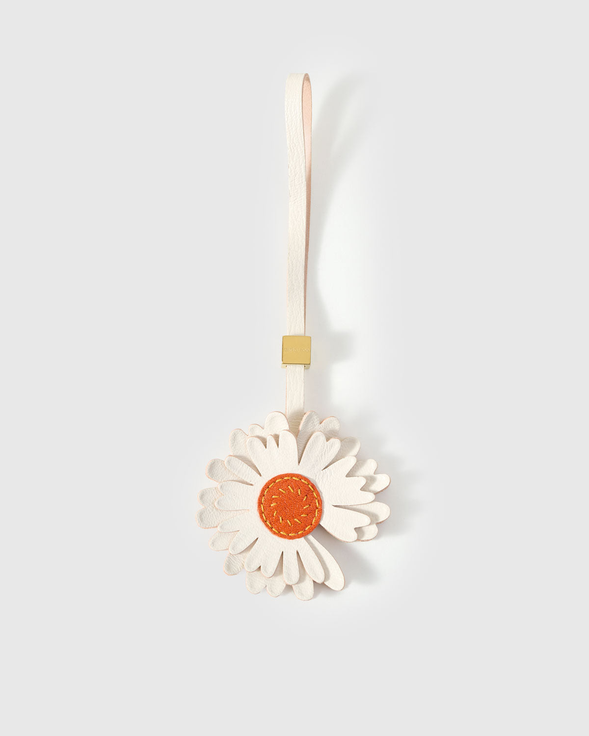 STICKYZOO Daisy Charm — white French Alran goatskin petals in two layered tiers with orange suede centre disc, 18K gold-plated hardware. 3-day handmade piece.