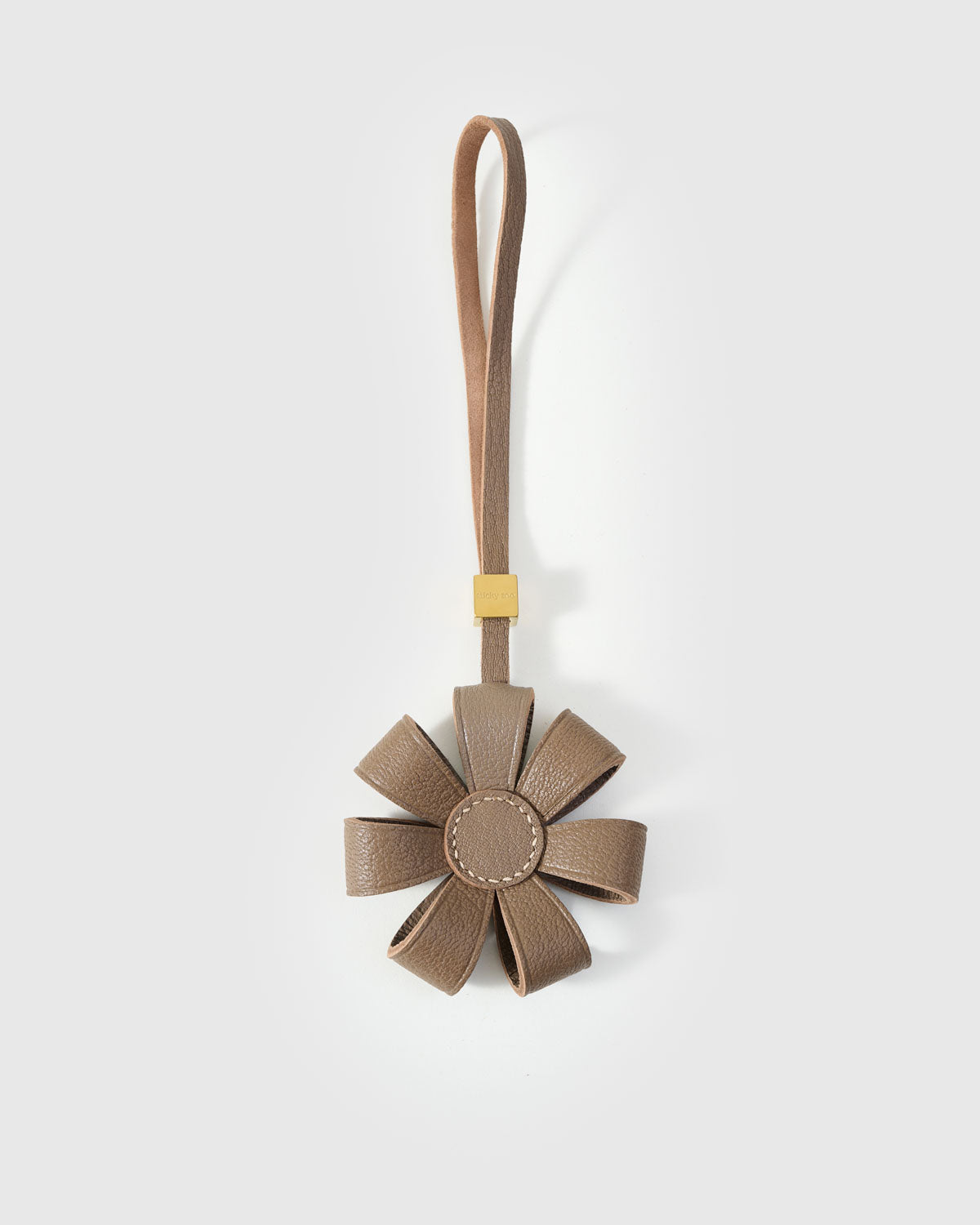 STICKYZOO Daisy Bag Charm in warm taupe French Alran goatskin — folded dimensional petals with tonal centre disc, 18K gold-plated hardware. 3-day handmade piece.