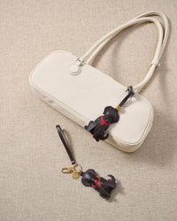 Close-up of handmade Golden Retriever leather bag charm — hand-stitched visible edges on French Alran goatskin, 18K gold-plated cube hardware. STICKYZOO.