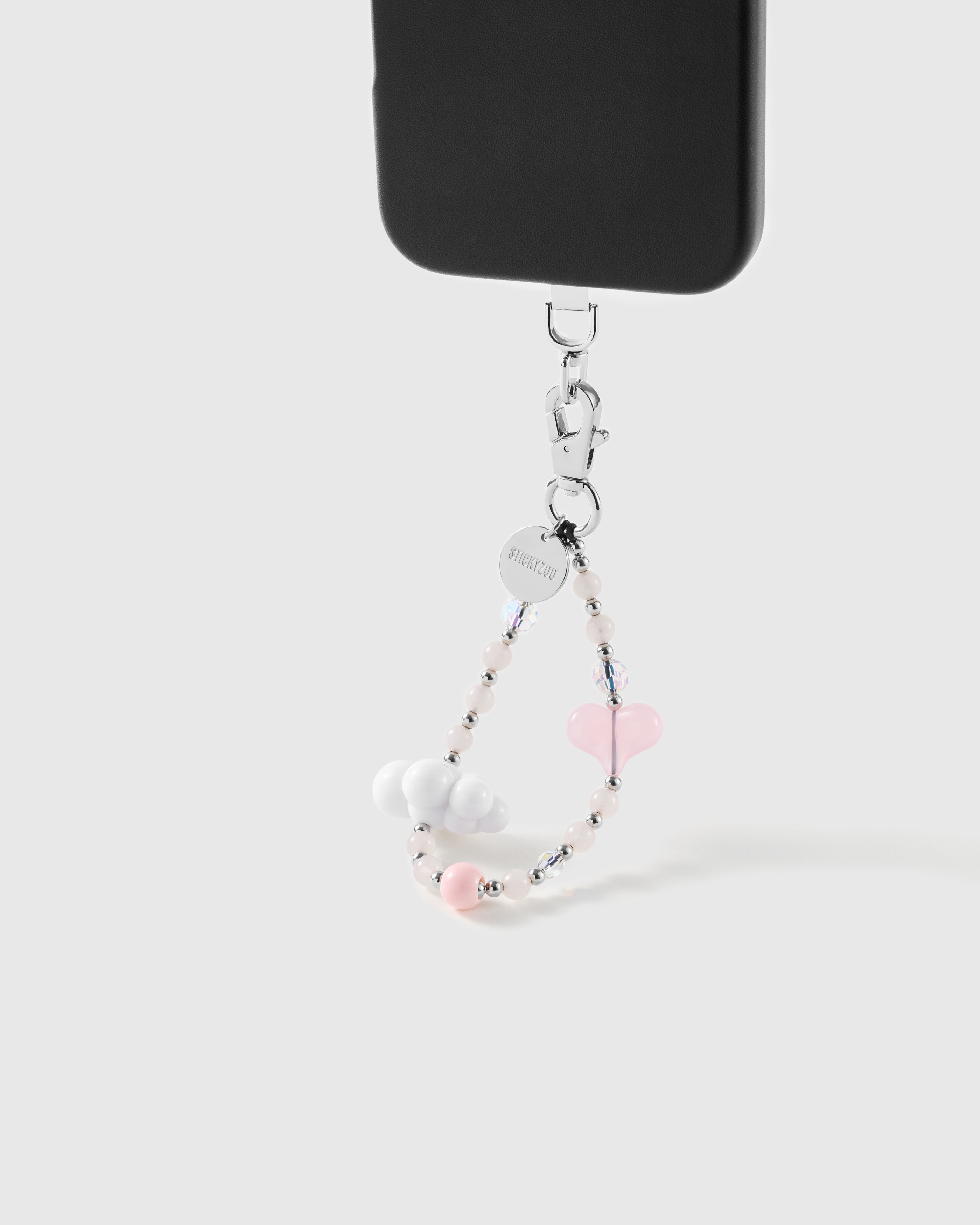 Blush Cloud wrist strap clipped to a black phone case for hands-free carry