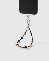 Puppy picnic charm wrist strap clipped to a black phone case for hands-free carry