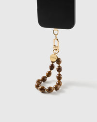 Amber swirl bead wrist strap clipped to a black phone case for hands-free carry