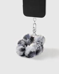 Smoke Pom wrist strap clipped to a black phone case for hands-free carry