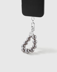 Grey pearl wrist strap clipped to a black phone case for hands-free carry