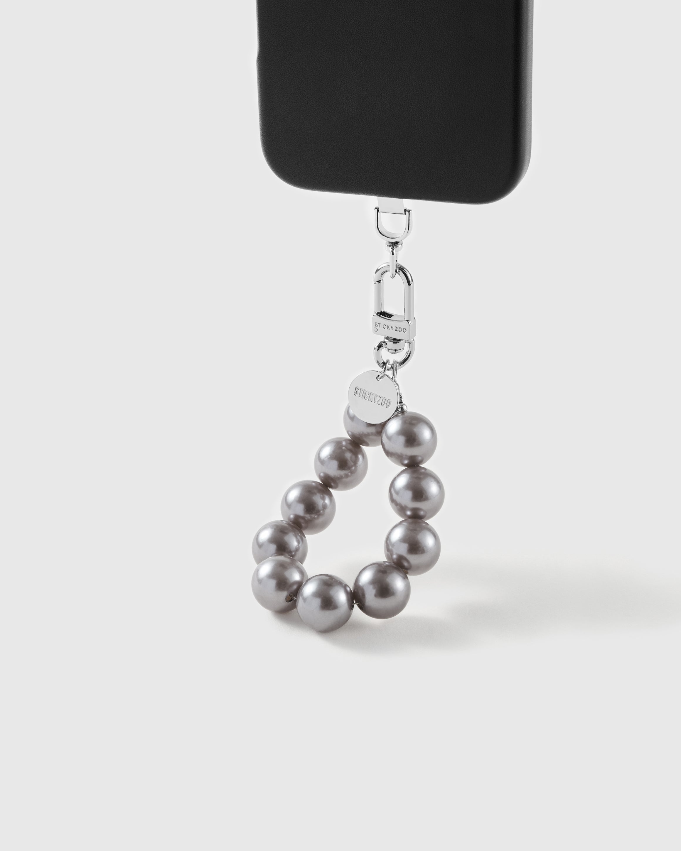 Grey pearl wrist strap clipped to a black phone case for hands-free carry