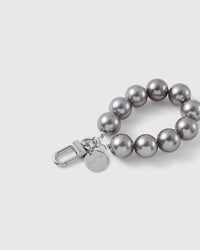 Close-up of the silver-tone hook, engraved STICKYZOO disc and grey pearl-style beads — soft even sheen