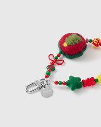 Close-up of the silver-tone hook, engraved STICKYZOO disc and the felted tree charm, wire bow, flocked star and glossy holiday beads — soft and tactile